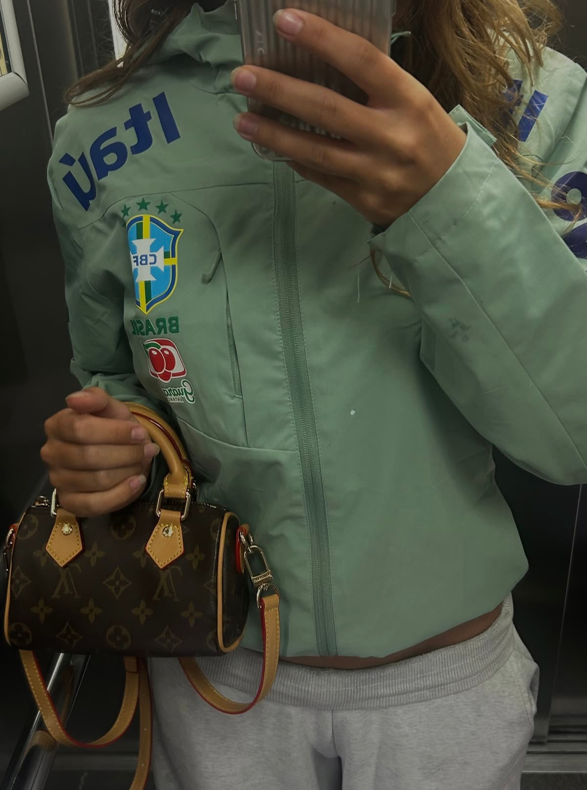 Light green jacket, grey jeans and a brown bag